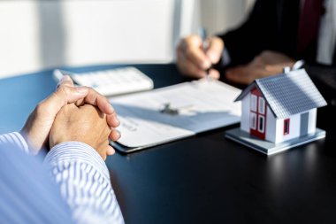 Kiralama şirketi çalışanı, kira sözleşmesini imzalamayı kabul eden müşterinin kira sözleşmesinin detaylarını ve şartlarını açıklayan belgeleri kontrol ediyor. Emlak kiralama fikirleri.