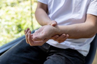 Bir insan bileğine tutunur, ki bu da işten gelen acıdan kaynaklanır, bilgisayarın başında uzun süre oturup yazmaktan gelen acı, vücudun birçok yerinde ağrıya neden olur. Office Sendromu kavramı.