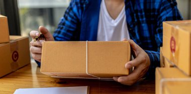 Paket kutusuna müşterilerin sevkiyat bilgilerini yazan Asyalı biri, bir online mağazası var, ürünlerini özel bir kurye şirketi aracılığıyla müşterilere gönderiyor. Çevrimiçi satış kavramı.