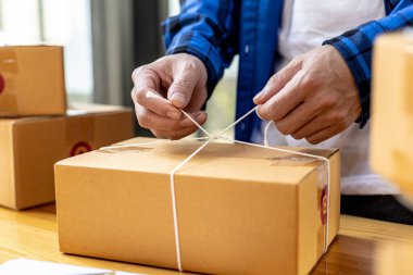 Bir Asyalı müşteri kutusuna paket bağlıyor, çevrimiçi bir mağazası var, özel bir nakliye şirketi aracılığıyla paketleyip gönderiyor. Çevrimiçi satış ve online alışveriş kavramları.