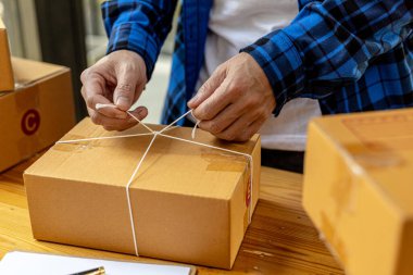 Bir Asyalı müşteri kutusuna paket bağlıyor, çevrimiçi bir mağazası var, özel bir nakliye şirketi aracılığıyla paketleyip gönderiyor. Çevrimiçi satış ve online alışveriş kavramları.