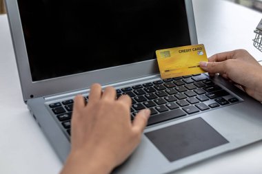 Kredi kartı tutan ve dizüstü bilgisayarda yazan bir kadın, bir İnternet alışveriş sitesinde sipariş verebilmek için kredi kartı bilgilerini dolduruyor. Çevrimiçi alışveriş ve kredi kartı ödeme kavramı