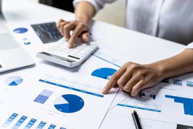 Beyaz hesap makinesi kullanan bir iş kadını, bir şirketin mali belgelerindeki sayısal verileri inceleyen bir finans işadamı, sayıların doğruluğunu doğrulamak için bir hesap makinesi kullanır..