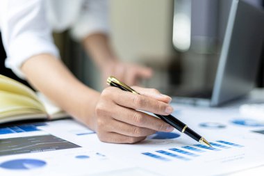 Şirketin mali bilgilerini gösteren bir tabloya işaret eden işkadını, şirketin mali bilgilerini harita halinde gösteren bir belge olan özel ofisinde oturuyor. Finansal kavramlar