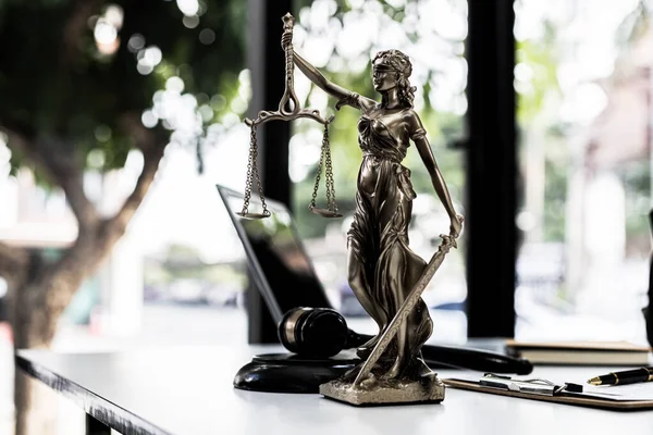 Lawyer\'s Desk On the table is a statue of Themis who is the goddess of justice and the hammer of justice, lawyers often praise her as a symbol of justice. Concept of law and justice.