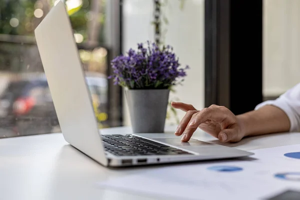 A businesswoman is checking company financial documents and using a laptop to talk to the chief financial officer through a messaging program. Concept of company financial management.