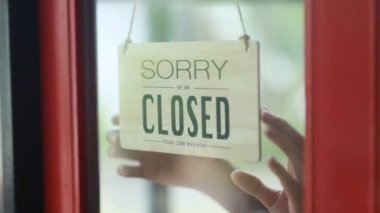 Bir çalışan kapanış tabağını tersine çevirdi, yemek ve içecek servisi yapan bir restoran, bir bayan garson dükkanı hazırladı ve mağazanın hizmet vermeye hazır olduğunu gösteren bir tabela açtı..