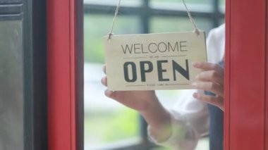 Bir çalışan, kapanış plaketini, yiyecek ve içecek servisi yapan bir restoranı geri çeviriyor ve bir bayan çalışan da mağazanın kapalı olduğunu söylemek için plaketi ters çeviriyor. Yiyecek ve içecek servisi kavramı.