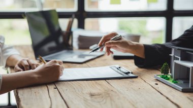 Rental company employee is discussing the details before the customer agrees to sign a rental contract, explaining the details and the terms and conditions of the rental. Real estate rental ideas.