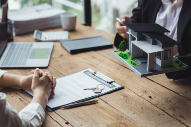 Rental company employee is discussing the details before the customer agrees to sign a rental contract, explaining the details and the terms and conditions of the rental. Real estate rental ideas.