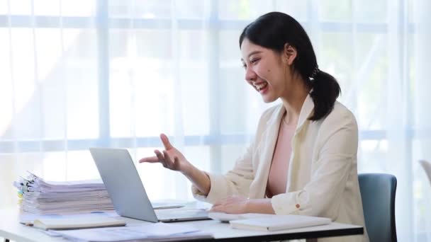 漂亮的亚洲女商人坐在她的私人办公室里 她通过笔记本电脑上的视频电话与她的伴侣交谈 她是一家初创公司的女执行官 财务管理的概念 — 图库视频影像