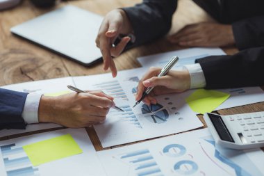 Konferans salonundaki bir masanın üstündeki kağıtlara işaret eden bir grup insan, finans ve muhasebe departmanıyla şirket denetim toplantısına katılan bir finans analisti. Buluşma konsepti.