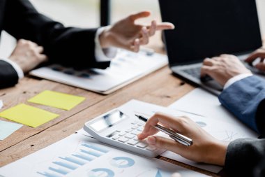 Bir şirketin mali belgelerindeki rakamları hesaplamak için hesap makinesi kullanan bir işadamı, şirketin nasıl büyüyeceğini planlamak için tarihsel finansal verileri analiz ediyor. Mali konsept.