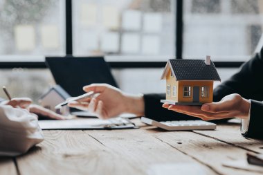 Real estate agents are carrying a housing model of the project to be forwarded to customers as home delivery. Real estate trading ideas and bank loans for buying and selling houses and land.