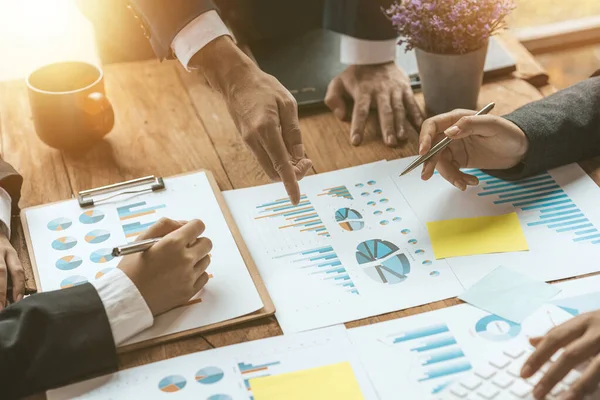 A group of people pointing to papers on a table in a conference room, a financial analyst attending a company audit meeting with the finance and accounting department. Meeting concept.