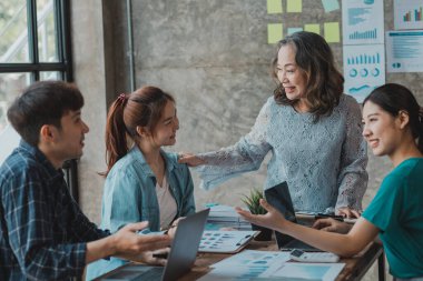 Girişim yöneticisi, planlamak ve tartışmak için yeni nesil çalışanlarla görüşüyor. O, modern bir zihniyete sahip deneyimli bir üst düzey yönetici. Girişim şirketinin yönetim kavramı.
