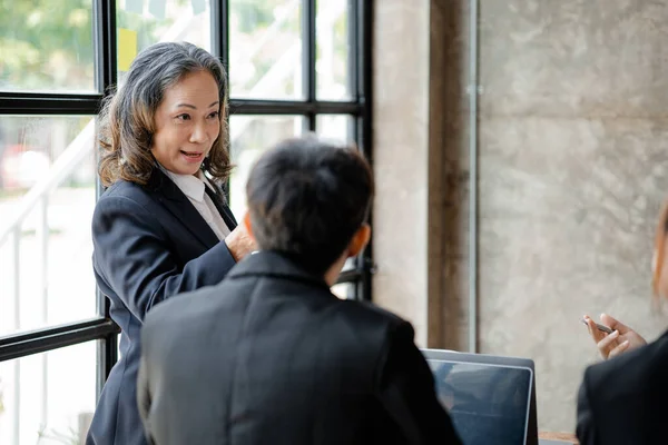 Senior businesswoman with senior executives talking in a meeting, she is meeting with department head staff at a conference room, senior female executives and new generation employees working together