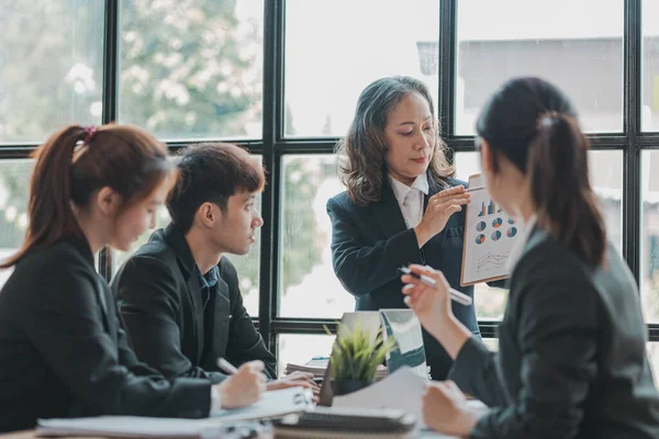 Senior businesswoman with senior executives talking in a meeting, she is meeting with department head staff at a conference room, senior female executives and new generation employees working together