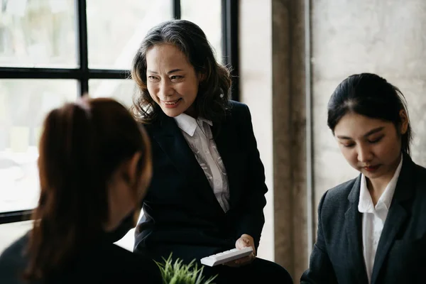 Senior businesswoman with senior executives talking in a meeting, she is meeting with department head staff at a conference room, senior female executives and new generation employees working together