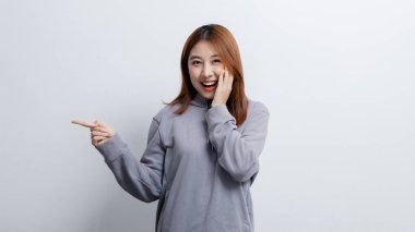 İlan metni için boş alanı işaret eden Asyalı kadın portresi, reklam ve tabela için kullanılan portre konsepti, beyaz arkaplan üzerinde izole edilmiş, kopyalama alanı.