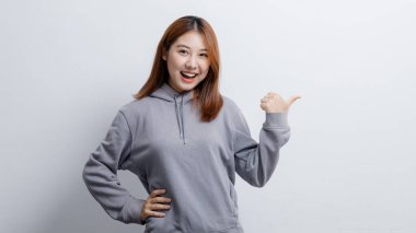 İlan metni için boş alanı işaret eden Asyalı kadın portresi, reklam ve tabela için kullanılan portre konsepti, beyaz arkaplan üzerinde izole edilmiş, kopyalama alanı.