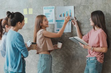 Bir grup Asyalı iş kadını ayakta dikiliyor ve konuşuyor. Yeni nesil konseptinden kazanç sağlamak ve işi büyütmek için ortaklaşa bir şirket ve bir işletme planı oluşturun..