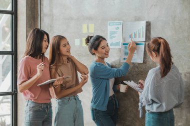 Bir grup Asyalı iş kadını ayakta dikiliyor ve konuşuyor. Yeni nesil konseptinden kazanç sağlamak ve işi büyütmek için ortaklaşa bir şirket ve bir işletme planı oluşturun..