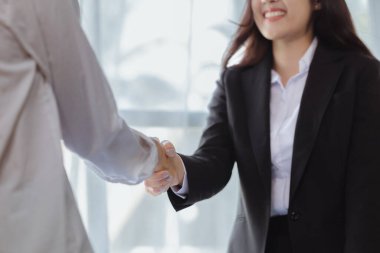 İki kadın el sıkışırken, iki iş kadını daha karlı büyüme yolları bulmak için beyin fırtınası ve pazarlama planlarını tartışmak üzere buluşurken el sıkışıyor. Karlı büyüme için işletme yönetimi fikirleri.