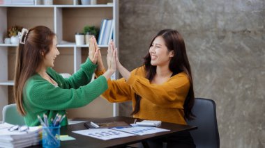 Keyif veren ve laptoplarındaki verilere bakan iki kadın, satış hedeflerini aşan ve kârlı bir büyüme sağlayan aylık satış özetine bakan iki iş kadını. Satış yönetimi kavramı