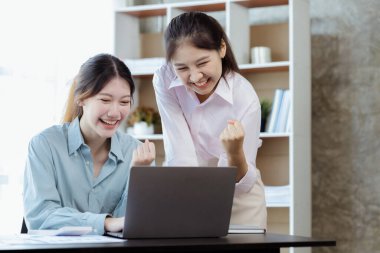 Keyif veren ve laptoplarındaki verilere bakan iki kadın, satış hedeflerini aşan ve kârlı bir büyüme sağlayan aylık satış özetine bakan iki iş kadını. Satış yönetimi kavramı