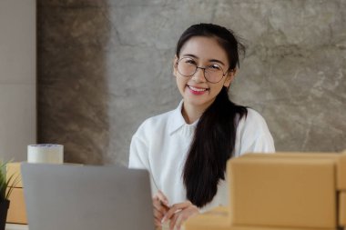 Güzel bir Asyalı işletme sahibi online bir dükkan açıyor, müşterilerin siparişlerini kontrol ediyor, bir kurye şirketi aracılığıyla mal gönderiyor, bir kadının online iş kurma kavramı.
