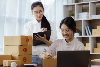 Güzel bir Asyalı işletme sahibi online bir dükkan açıyor, müşterilerin siparişlerini kontrol ediyor, bir kurye şirketi aracılığıyla mal gönderiyor, bir kadının online iş kurma kavramı.