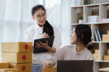 Güzel bir Asyalı işletme sahibi online bir dükkan açıyor, müşterilerin siparişlerini kontrol ediyor, bir kurye şirketi aracılığıyla mal gönderiyor, bir kadının online iş kurma kavramı.