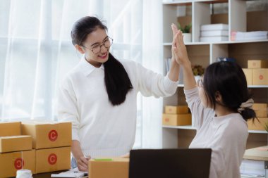 Mutlu bir ifade sergileyen iki kadın müşterilerin siparişlerini kontrol ediyor, bir kurye şirketi aracılığıyla mal gönderiyorlar, internet üzerinden iş kuran bir kadın konsepti..