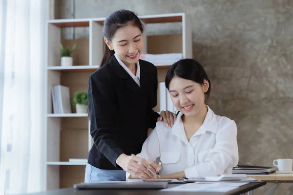 Atmosphere in the office of a startup company, two female employees are discussing, brainstorming ideas to working on summaries and marketing plans to increase sales and prepare reports to managers.