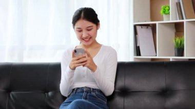 Oturma odasındaki kanepede akıllı telefon oynayan bir kadın, yoğun bir iş gününden sonra hafta sonları dinleniyor, internetten alışveriş yapıyor ve kredi kartıyla ödüyor. Kredi kartı ödeme kavramı.