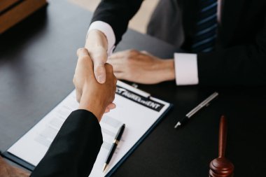 Lawyers shake hands with clients who come to testify in the case of embezzlement from business partners who jointly invest in the business. The concept of hiring a lawyer for legal proceedings.
