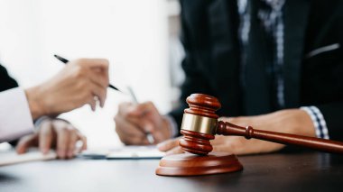 Avukatın odasındaki masada duran çekiç tokmağı adaletle yargılamak ve avukatın davasını müvekkiline karşı savunmak için kanunu kullanıyor. Hukuk ve adalet kavramı.