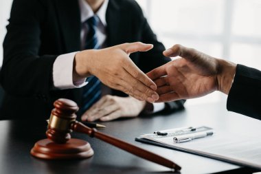 Avukatlar, bu işe ortak yatırım yapan iş ortaklarının zimmetine para geçirme davasında tanıklık etmeye gelen müşterilerle tokalaşıyorlar. Yasal işlemler için avukat tutma kavramı.