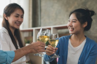 Beyaz şarap bardaklarını tokuşturan genç Asyalılar, yeni yıl partileri, yıllık şirket partileri, alkollü içecekler. Şirket çalışanları parti yemekleri, kutlamalar..