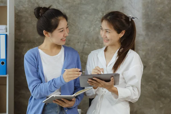 Two Asian women chatting, business women conversing in a conference room, young entrepreneurs run and run a startup, young and energetic group run the company. Startup company concept.