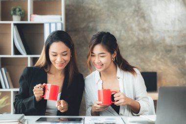 Atmosphere in the office of a startup company, two female employees are discussing, brainstorming ideas to working on summaries and marketing plans to increase sales and prepare reports to managers.