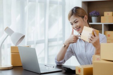 Güzel bir Asyalı işletme sahibi online bir dükkan açıyor, müşterilerin siparişlerini kontrol ediyor, bir kurye şirketi aracılığıyla mal gönderiyor, bir kadının online iş kurma kavramı.