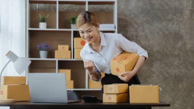 Güzel bir Asyalı işletme sahibi online bir dükkan açıyor, müşterilerin siparişlerini kontrol ediyor, bir kurye şirketi aracılığıyla mal gönderiyor, bir kadının online iş kurma kavramı.