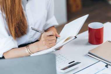 Asyalı bir bayan çalışan şirket ofisinde oturur ve notlar alır. Girişimci bir şirketin finans ve vergi departmanında çalışıyor. Kurumsal finans ve vergi yönetimi kavramı.