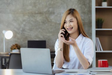 Telefonda konuşan Asyalı bir kadın, bir girişim şirketinde satış elemanı, ürün ve promosyon satmak için müşterileri arıyor. Telefon kanalları aracılığıyla ürün satma kavramı.