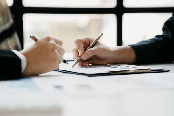 Two businessmen pointed to the material for the meeting, working together to plan to develop and solve common business problems. Concept of business management for growth and quality.