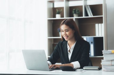 Business woman working in a private office, she is reviewing the company's financial documents sent from the finance department before he takes it to a meeting with a business partner. Financial concept.