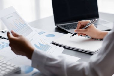 Bir iş kadını not defterine notlar alıyor, şirketin mali belgelerini kontrol ediyor ve düzeltilmesi için maliye müdürüne düzeltici raporlar götürüyor. Finans kavramı.