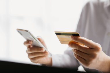 Kredi kartı tutan bir kadın, internet üzerinden mal ve hizmetleri ödemek için kredi kartı kullanıyor, online alışveriş için kredi kartı kullanma, internet sitesinden mal ve hizmet sipariş etme kavramı.